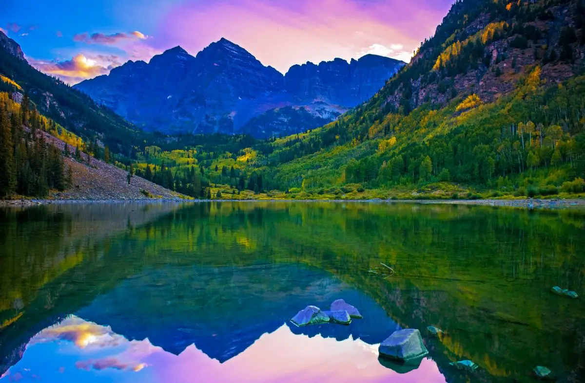 green trees and mountains near lake during daytime